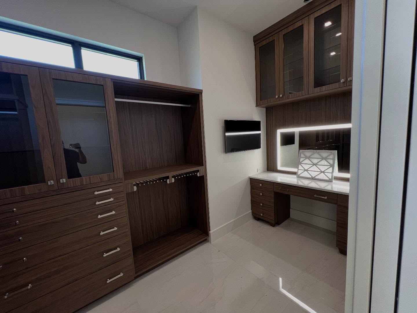 Walnut-toned closet cabinetry with illuminated vanity